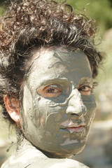 Young woman having a mud bath.