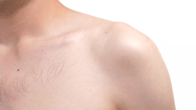 Closeup on the shoulder area of a young man. Human body part over a white screen background.