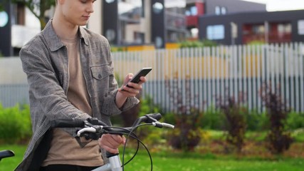 lifestyle, transport and people concept - young man or teenage boy with bicycle and smartphone in city - Powered by Adobe