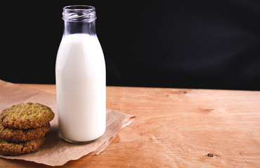 Homemade almond milk in glass bootle with oatmeal cookies on the wooden table. Organic alternative milk. Copy space. Cookies with milk.