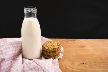 Homemade almond milk in glass bootle with oatmeal cookies on the wooden table. Organic alternative milk. Copy space. Cookies with milk.