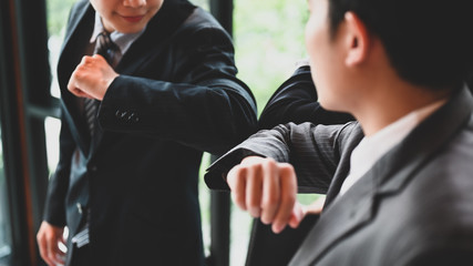 Businesspeople are greeting each other with the elbow. Elbow bumps greeting style to prevent contact and virus spread.