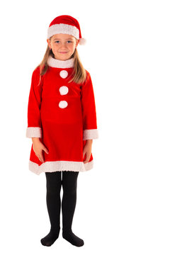 Full Length Portrait Of Beautiful 8 Year Old Girl Standing With Arms Next To Body Wearing Red Christmas Costume With A Red Dress, Santa Claus Hat And Black Stockings Isolated On White