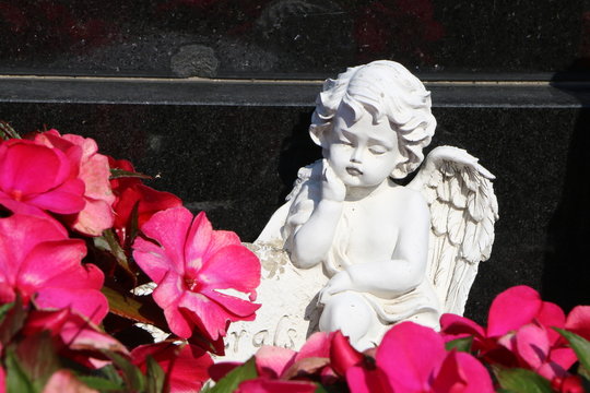 Trauriger Engel auf einem Grab mit roten Blüten, Friedhof, Tod, Gedenken, Trauer, Grabpflege