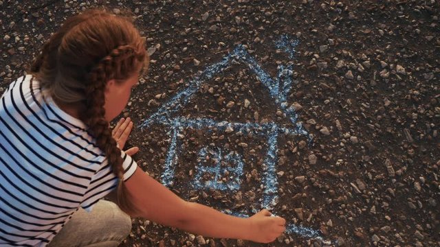 child kid draw a house on the asphalt with chalk . childhood mortgage dream kid concept. little girl playing draws with chalk big house. concept loan mortgage for a dream residential home building