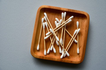 Bamboo cotton swabs on a wooden plate. Blue paper background. Zero waste concept. View from above. Copy space.