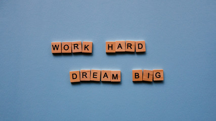 Words "Work hard. Dream big" on a blue paper background. Motivating web banner.