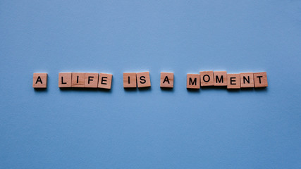 Words "A life is a moment" on a blue paper background. Motivating web banner.