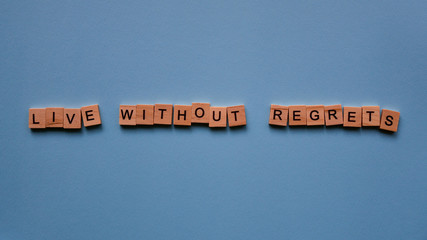 Words "Live without regrets" on a blue paper background. Motivating web banner.