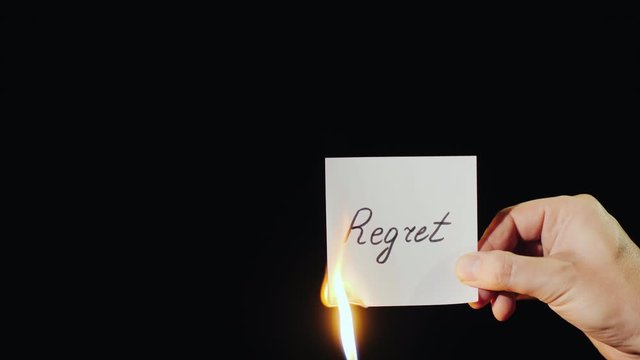 Man burns a paper with the inscription Regret