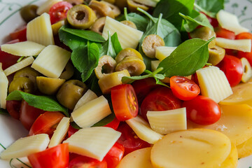 Salada com manjericão, tomate cereja, azeitonas e queijo mussarela.