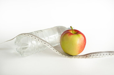 apple with tape measure, measuring tape isolated on white background. Apple and transparent bottle of water isolated on white background - diet concept