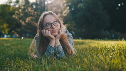 Pretty young caucasian woman having a break from work or school in the park, relaxing on the grass. Copy space . High quality photo