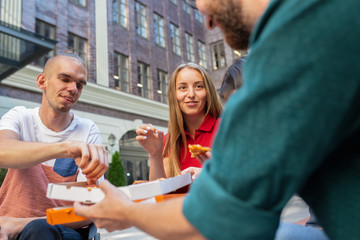 Pizza time. Group of friends taking a stroll on city's street in summer day. Handicapped man with...