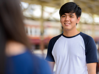 Happy young Asian tourist couple travelling together at the railway station