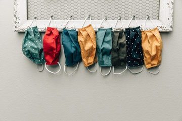 A row and variety of colorful protective face masks hanging on a home bulletin type clipboard for going back to work or back to school  for easy access with copy space