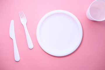 cutlery and empty plate on pink background top down