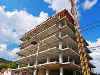Concrete frame structure of a new multi-story apartment building in construction and crane