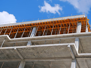 Closeup of concrete frame structure showing formwork system for concrete slab sustained by steel props. New multi-story apartment building in construction.