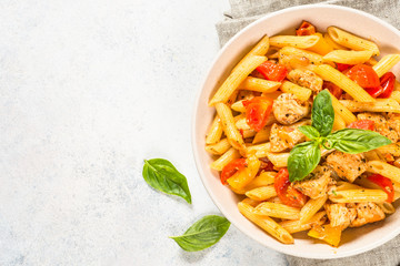 Pasta with chicken and vegetables at white table.