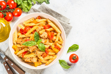 Pasta with chicken and vegetables at white table.