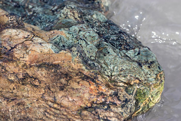 Natural texture: yellow-blue stone in the water of the river under natural light on a sunny summer day.
