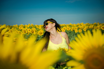Obraz na płótnie Canvas Cheerful girl in summer. Sunflower field. Girl and sunflowers. Bright happy woman summer. Girl in a yellow dress and yellow flowers