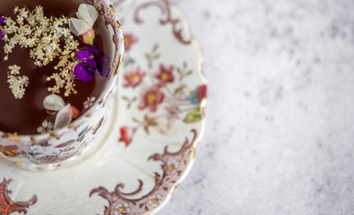 Obraz na płótnie Canvas Closeup of a floral vitage tea cup with some fresh flower petals