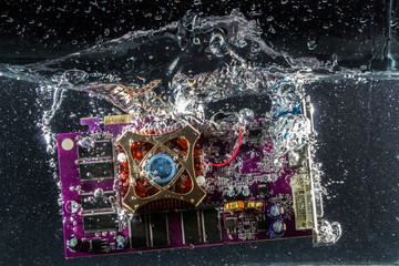 Video card adapter splashes and air bubbles falling into the water on a black background