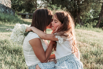 Young mother and her little daughter hugging. Outdoor photo