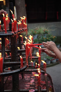 A visitor burns Incense sticks on the fire of burning candle and preparing for pray at Leshan Grand Buddha temple in Leshan, Sichuan, China