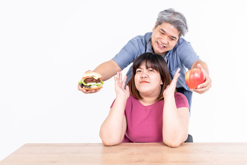 Fototapeta na wymiar Portrait images of Asian cople, The husband delivered hamburgers and apple for his wife to choose from, On white background, concept fat woman to weight control and health care
