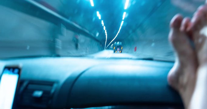Hyperlapse of driving a car in the tunnel. The camera on the hood of the car. Time lapse on the highway. Bare feet of a girl on the dashboard. Abstract smooth lines.
