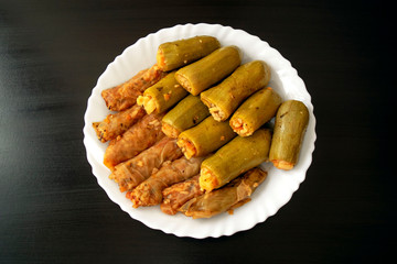 Traditional stuffed squash and cabbage rolls on white plate on dark wooden background. Famous traditional Middle East, Egyptian, Asian cuisine. Mahshi or mahshy, stuffed vegetables.