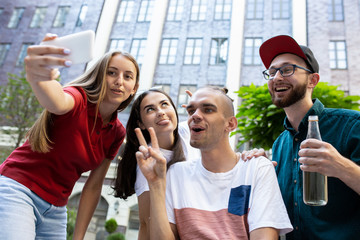 Taking selfie. Group of friends taking a stroll on city's street in summer day. Handicapped man...