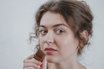 Pretty girl eating chocolate. Close-up portrait, delicious food, sweets. On white background