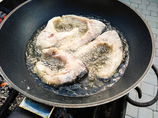 Close-up pieces of fish fried on a pan in oil. Delicious fried carp. The fish is fried in a pan on the grill.