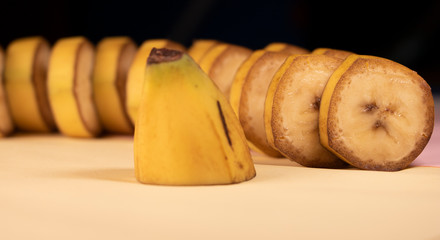 Sliced circles of unpeeled banana slices on a yellow background.