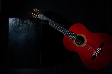 spanish classical red guitar with flamenco cajon on a black background