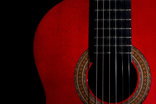 spanish classical red guitar close-up on a black background, left copy space