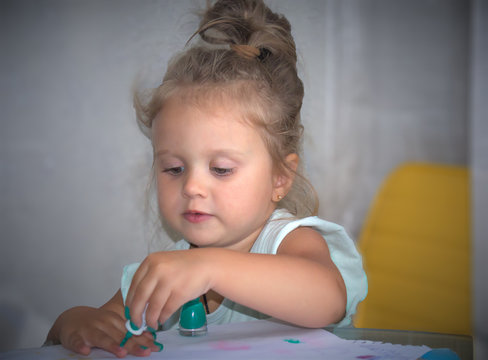 little girl paints her nails with green nail polish