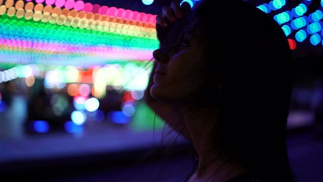 Young woman looking at the lights in amusement park in the night