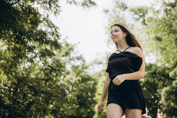 A teenage girl is having a walk in a green city park
