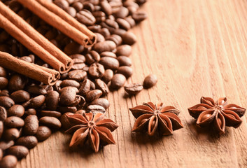 Many grains of coffee, anise and cinnamon lie on a wooden surface