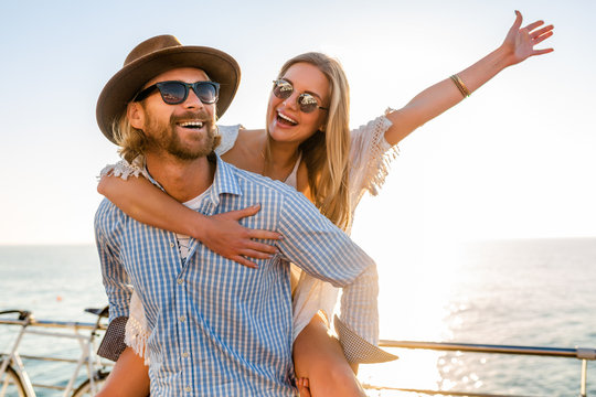 attractive happy couple laughing traveling in summer by sea, man and woman wearing sunglasses, boho hipster style fashion having fun together