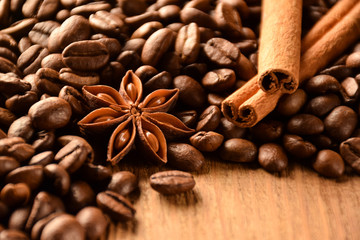 Many grains of coffee, anise and cinnamon lie on a wooden surface