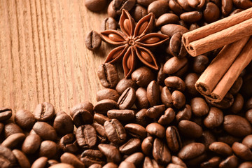 Many grains of coffee, anise and cinnamon lie on a wooden surface