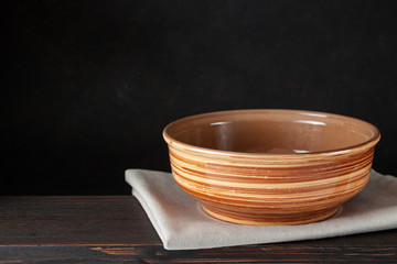 Empty bowl plate on wooden table over dark brown background