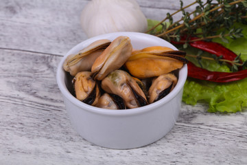 Pickled mussels in the bowl served pepper, garlic and salad