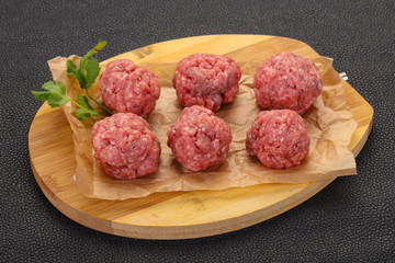 Raw meatball over wooden background